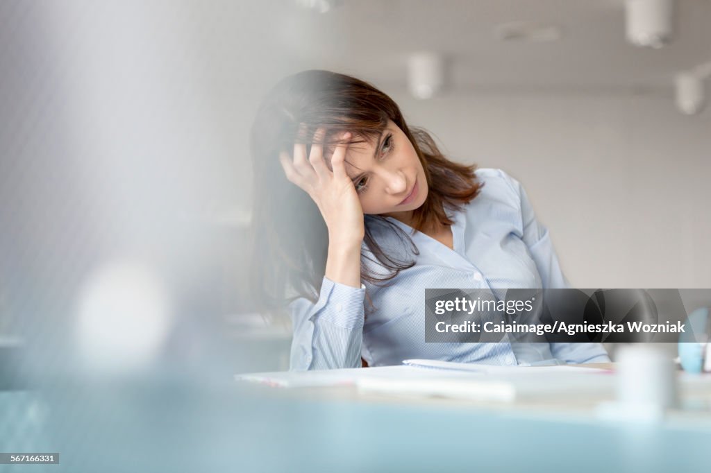 Tired businesswoman with head in hands looking away