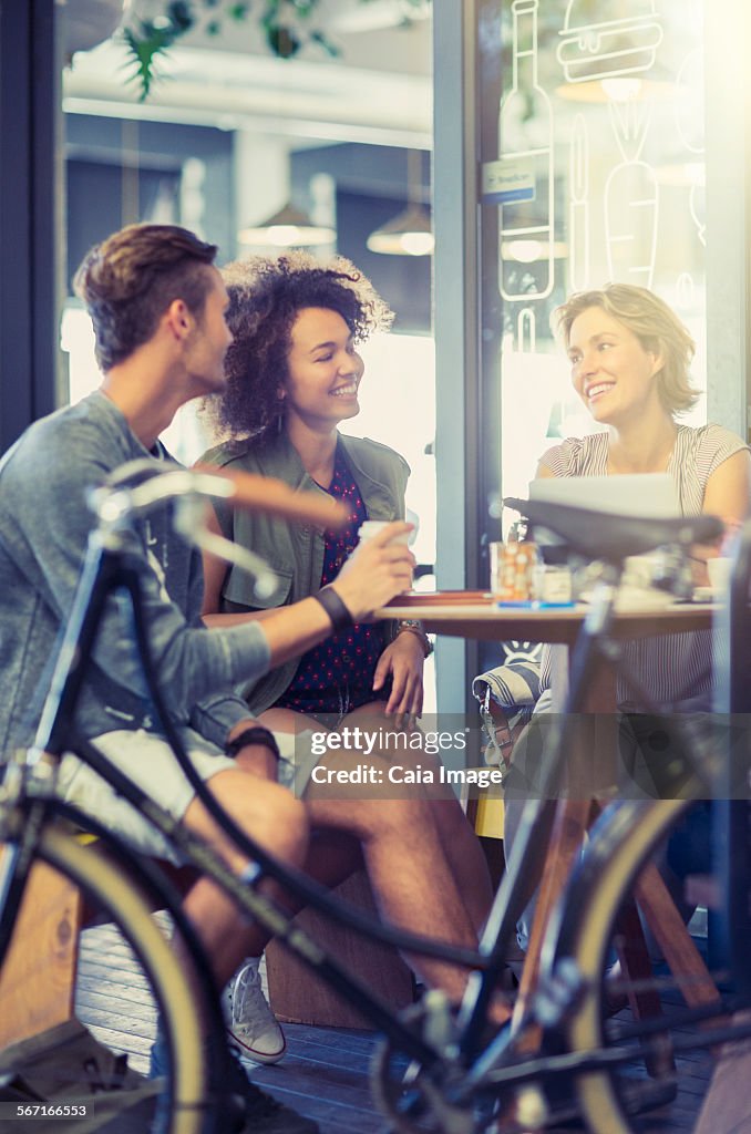 Friends hanging out at cafe table behind bicycle
