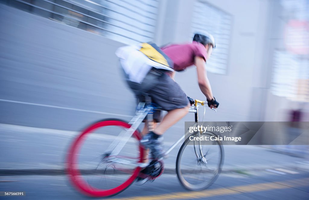 Bicycle messenger speeding down urban street