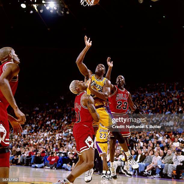 Magic Johnson of the Los Angeles Lakers drives to the basket against Dennis Rodman and Michael Jordan of the Chicago Bulls during an NBA game at the...