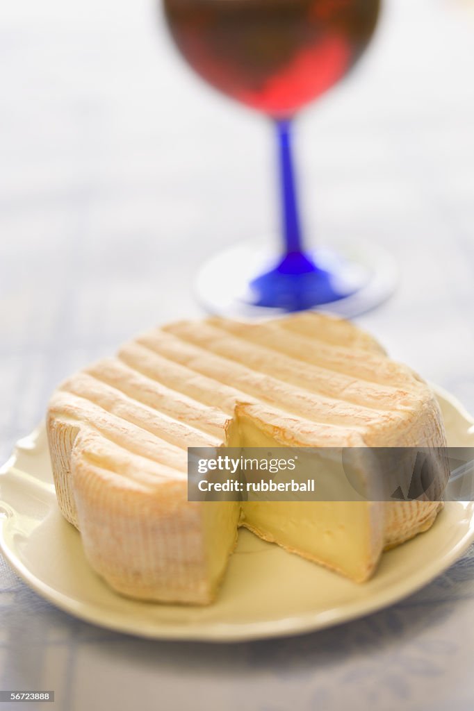 Close-up of soft cheese with a glass of red wine