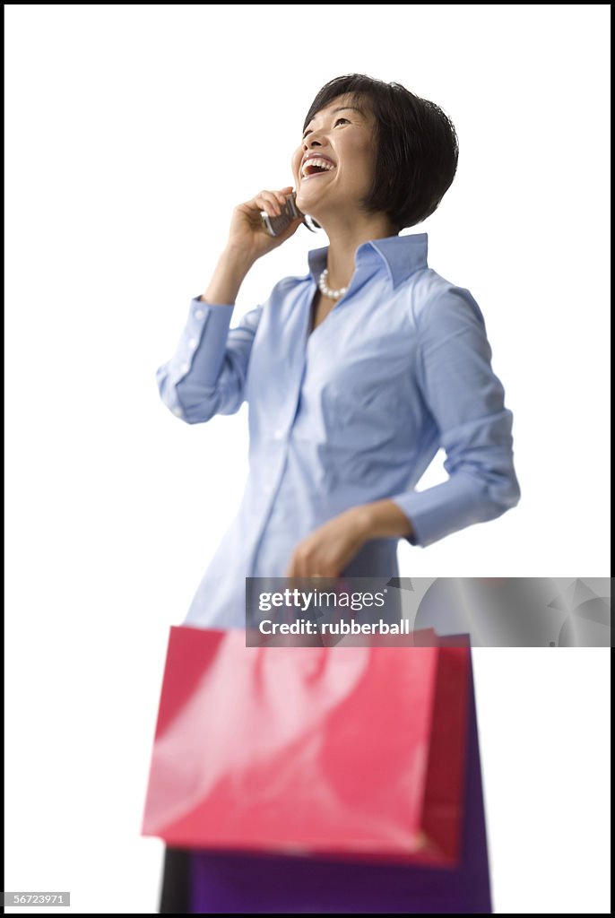 Mid adult woman holding shopping bags and talking on a cell phone