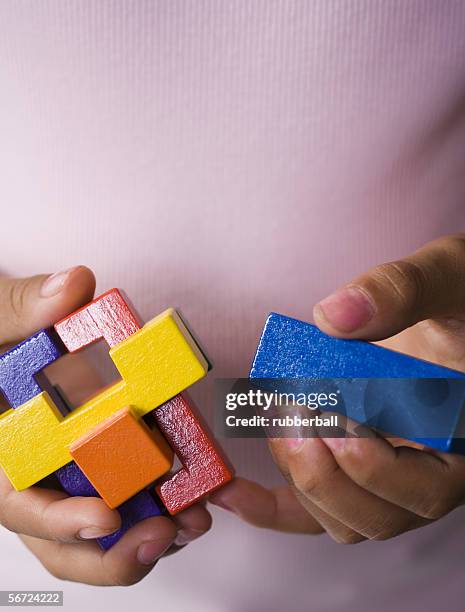 mid section view of a woman trying to piece together a cube puzzle - knoten lösen stock-fotos und bilder