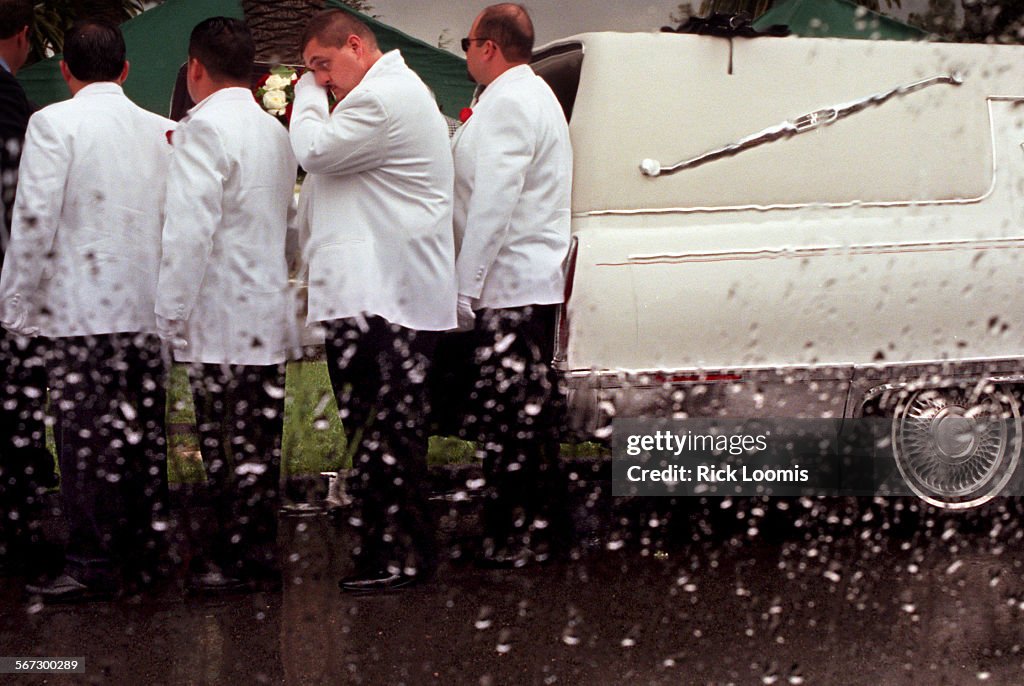 ME.murofuneral.casket.0407.RLSanta AnaA pallbearer wipes his eye as he helps move the casket of 