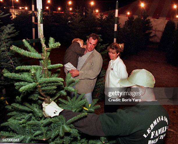 An employe of Lebman and Sons Xmas Tree lot shows tree to Kevin, Owen and Andrea Burke of Chatsworth. Photo made 121399.