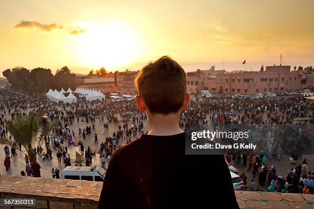 boy looking out onto crowded square - djemma el fna square 個照片及圖片檔