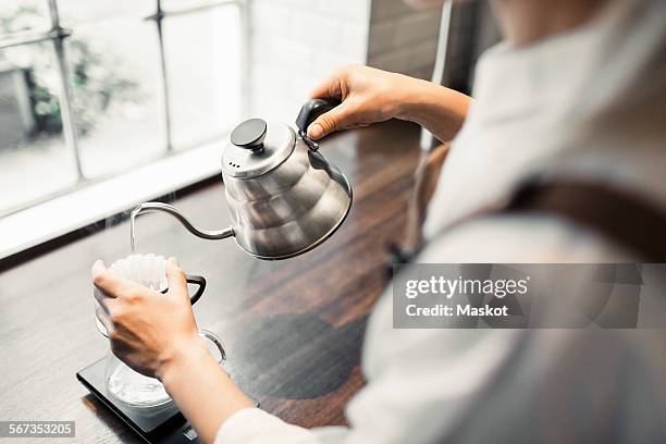 cropped image of female barista pouring boiling water in coffee filter at cafe - filterkaffee stock-fotos und bilder