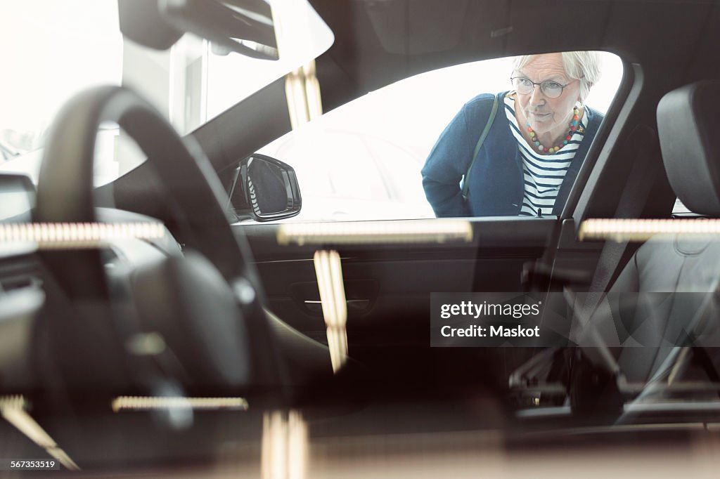 Senior woman admiring car displayed in store