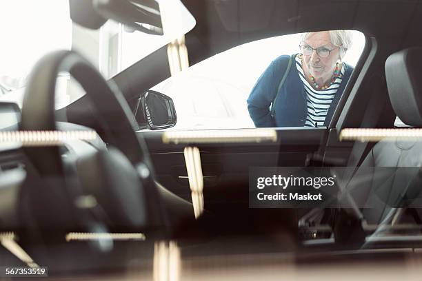 senior woman admiring car displayed in store - car display background stock pictures, royalty-free photos & images