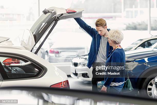 mother and son examining car in dealership shop - new car stock pictures, royalty-free photos & images