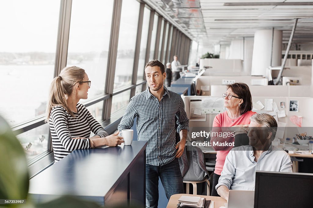 Business people discussing at cubicle in office