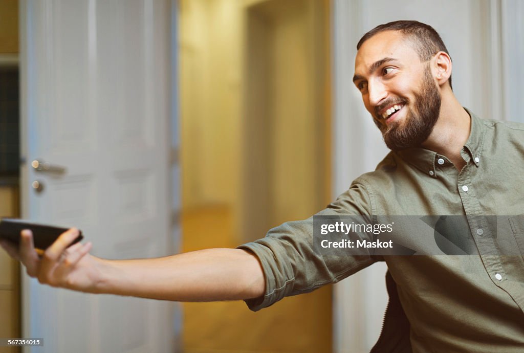 Happy businessman passing mobile phone in office