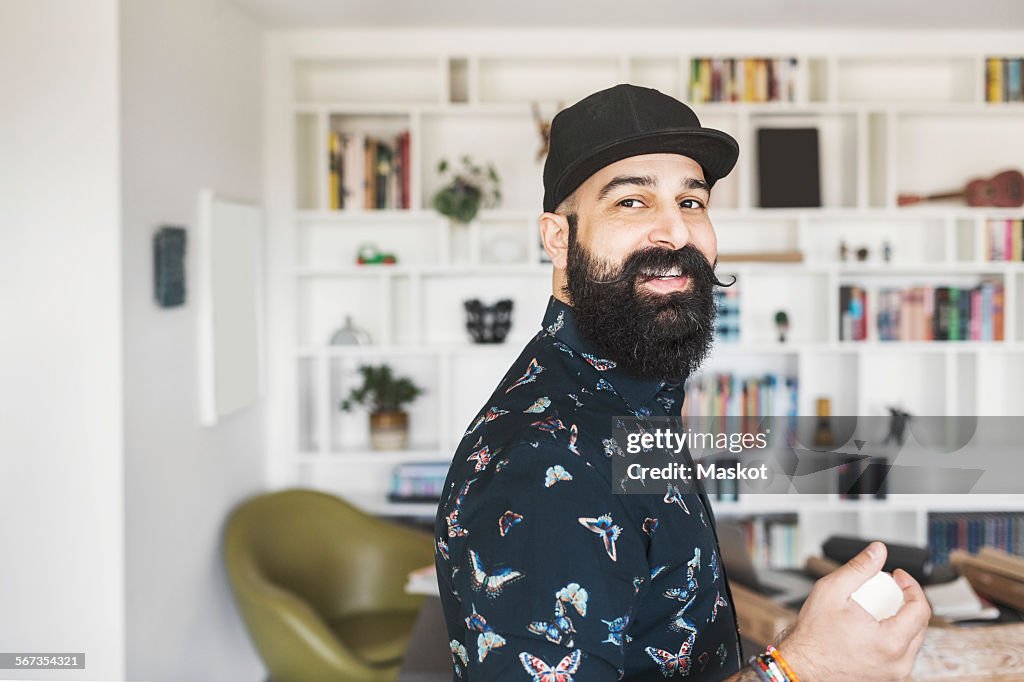 Side view of portrait of happy male architect standing in home office