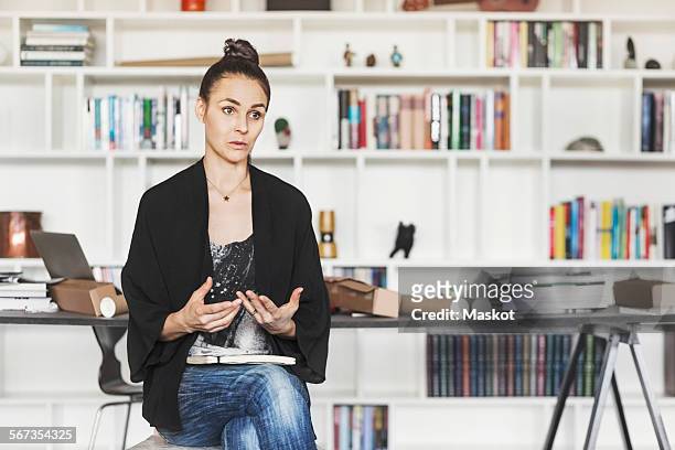 female architect gesturing while explaining at home office - director chair bildbanksfoton och bilder