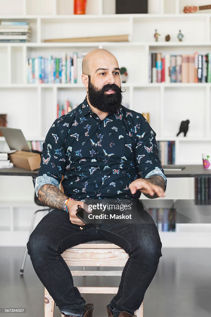 Male architect gesturing while sitting in home office