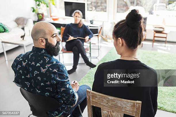 couple talking to woman taking notes - direttore artistico foto e immagini stock