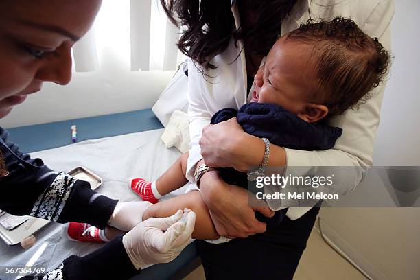 Medical assistant Daisi Minor, left, gives an MMR vaccine to Kristian Richard being held by his mother Natasha, at the Medical Arts Pediatric Med...