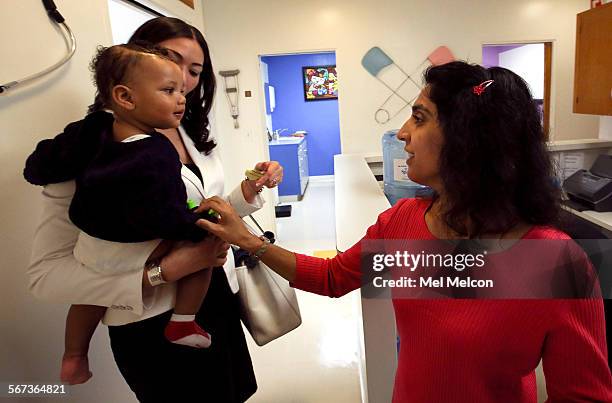 Dr. Monica Asnani, right, says goodbye to Kristian Richard being held by his mother Natasha, after the baby was given an MMR vaccine at the Medical...