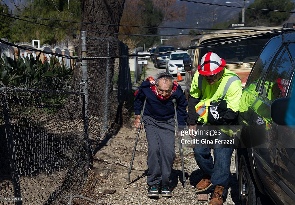 FONTANA, CA - JANUARY 24, 2015: A Southern California Edison worker escorts a resident to his home u