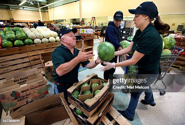 Produce manager Louie Jimenez, left, tosses a watermelon to Ashley Craddock, while unpacking melons inside a Haggen grocery store, formerly an...