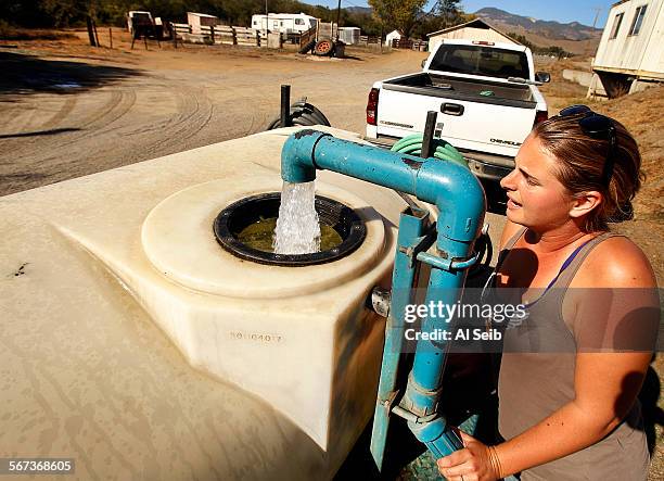 Heather Menges fills her 500-gallon water tank from the well of San Simeon Creek rancher Clyde Warren who sells Cambrians non-potable water for three...