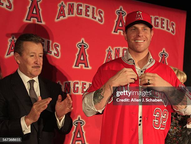 Los Angeles Angels owner Arte Moreno applauds at the news conference introducing free-agent signee Josh Hamilton, right, at ESPN Zone, Downtown...