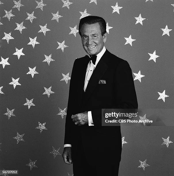 American game show host Bob Barker stands in black tie before a backdrop emblazoned with stars in a publicity photo, July 1, 1986.