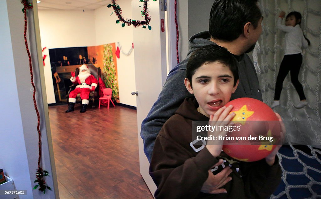 NORTHRIDGE, CA - DECEMBER 11, 2014: Jesus Haro holds son Isaiah, 14, as he and wife Yolanda try to