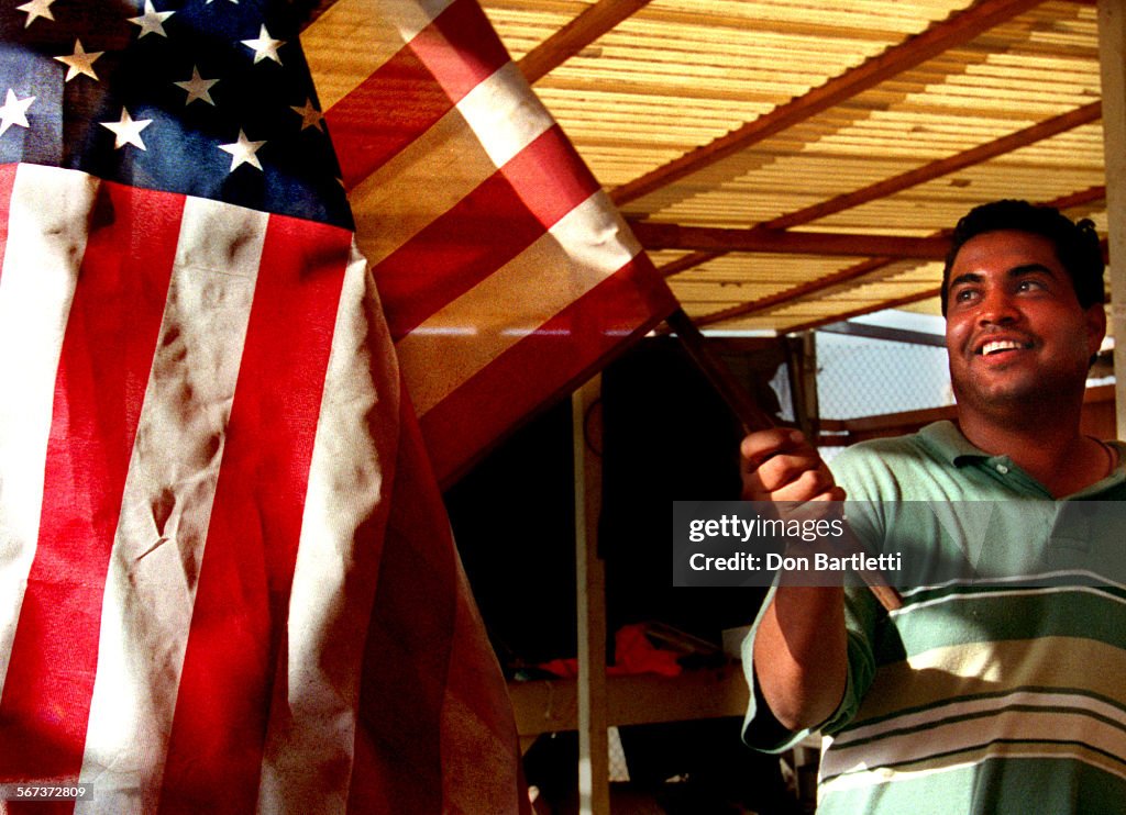 AA.Segunda.Corona.DB.9/24/97Ensenada.Carlos Corona, picks up a US flag at his segunda store in E