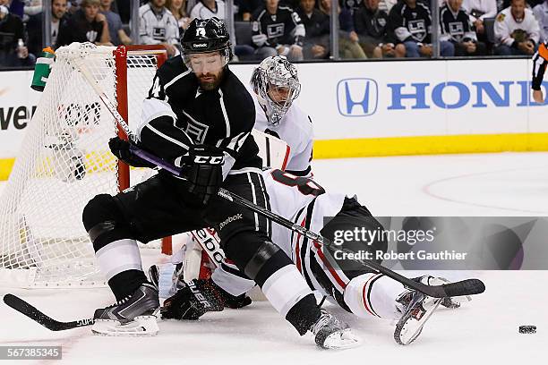 Kings forward Justin Williams is knocked off the puck as he tries to shoot past Blackhawks goalie Corey Crawford and defenseman Nick Leddy during...