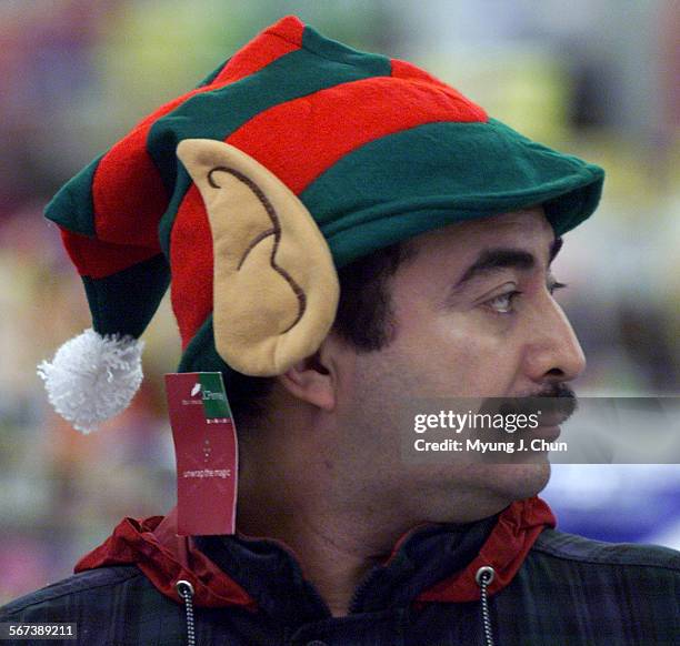 Rene Rosa of North Hills gets into the holiday spirit with an elf hat while waiting in line at the Panorama City Mall WalMart on Friday morning....