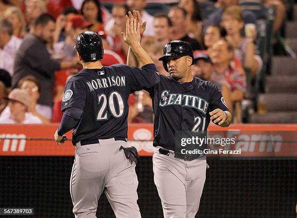 Seattle Mariners first baseman Logan Morrison gets a high five from Seattle Mariners designated hitter Kendrys Morales on a double by Seattle...