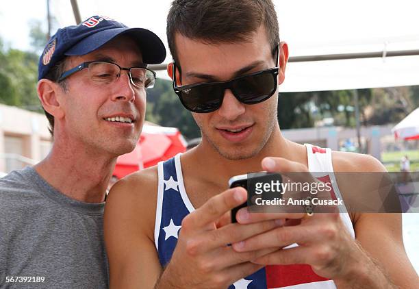 Douglas McCrory, left, looks at photos that his son Nick McCrory, right took of his brother Lucas McCrory who has dwarfism, as Lucas competes in the...