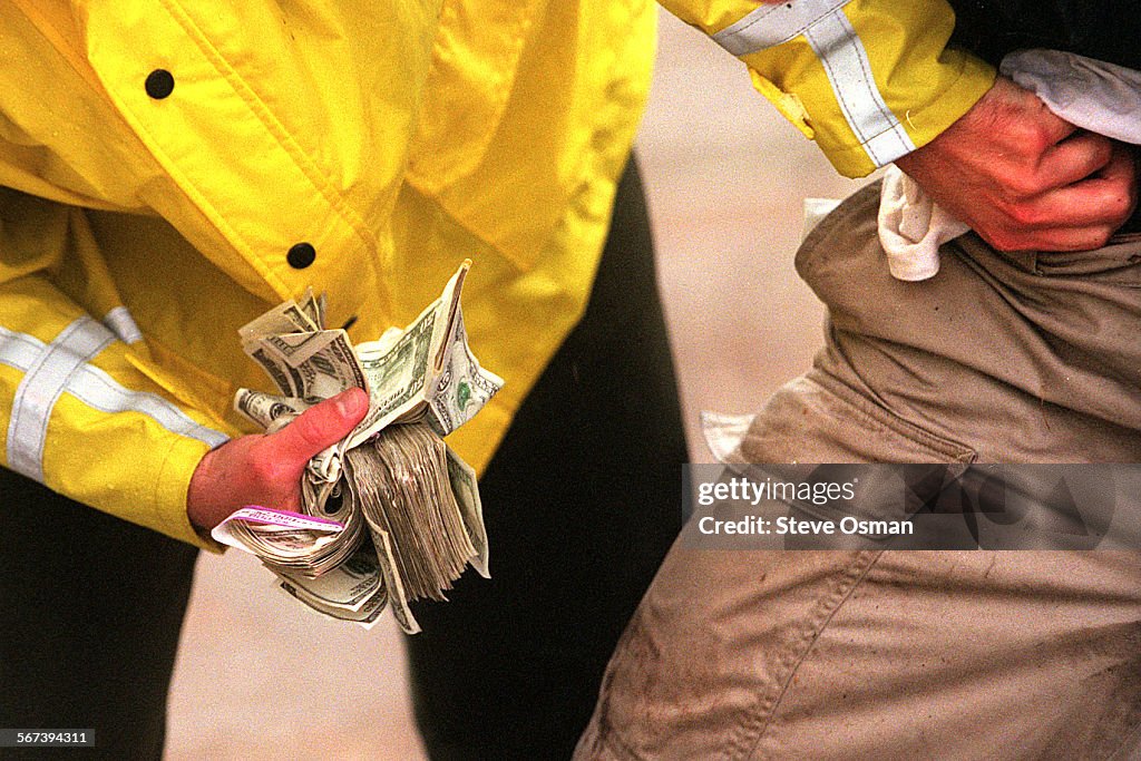 A Ventura County Sheriff's deputy pulls wads of money from the pockets of a suspected bank robber on