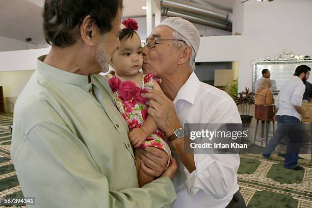 After Friday prayers on July 04, 2014 Rahmat Phyakul, right, plants a kiss on the cheeks of 1-year-old Zaina Khan, center, held by her grandfather...