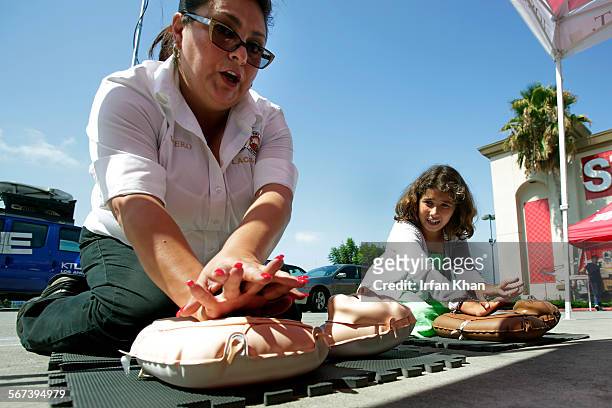 Los Angeles County Fire community services representative Rosemary Vivero, left, shows 9-year-old Francesca Krikorian how to perform CPR at the...