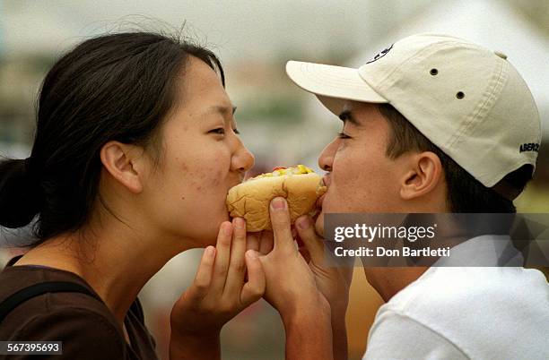 Fair.Yi.DB.090498.HuntingtonBeach.  Jessika Yi and Ed Vallesteros both of Long Beach, share a hot dog at the Main Street ArtAFair. Friends...