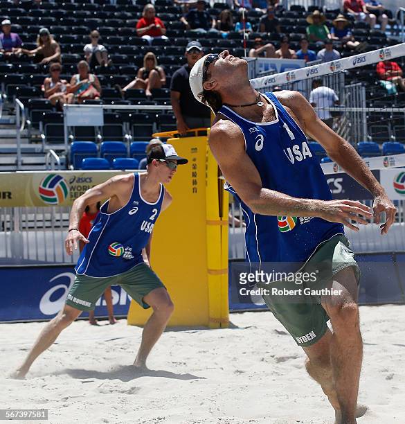 John Hyden right, chases a ball as his teammate Tri Bourne positions himself at the net during pool play on center court against a team from Poland...