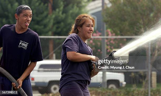 Monroe High School seniors Oscar Rodriguez and Angelina Alvarez spray a stream of water during a competition in the McComb Fire Academy class at...