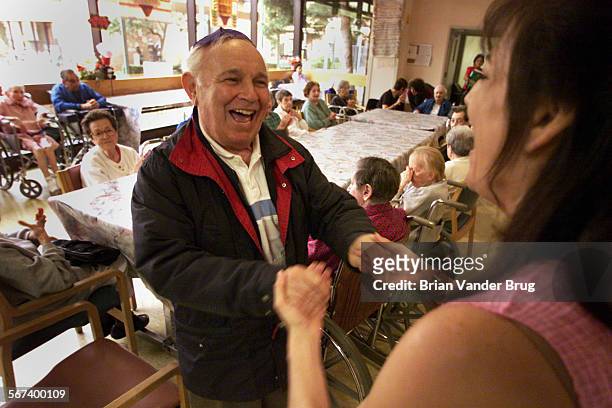 Beth Elliott, right, dances with former cantor William Nussen, left, during 'Hava Nagila' song at workshop at the Jewish Home for the Aging. Elliott,...