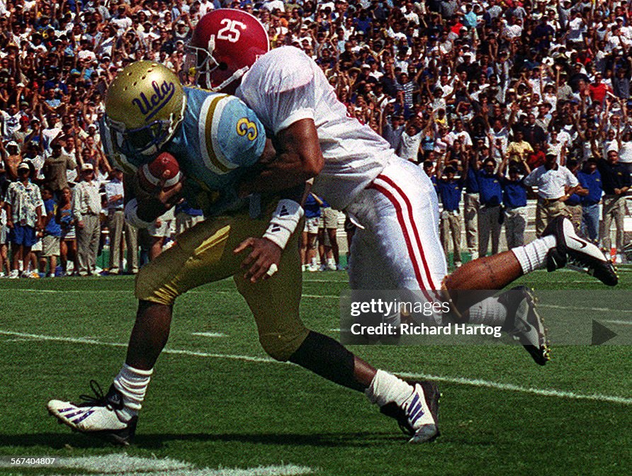 UCLA flanker Freddie Mitchell, left, carries Alabama defensive back Hirchel (cq) Bolden on his back 