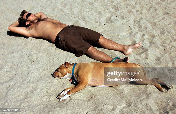 Julian Smith of El Monte, relaxes with his dog, Pup, a 6 year old pit bull, while taking in the sun at Santa Monica Beach on Wednesday afternoon,...