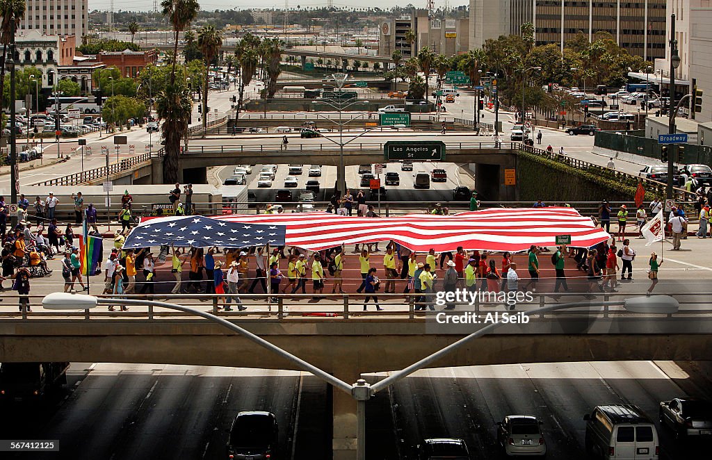 LOS ANGELES, CA - MAY 01, 2014 - Protesters hoists a giant American flag as they march South on Broa