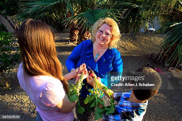 Bridgette Sullenger, hospice bereavement coordinator, picks radishes from her garden with her children Julia left, and Vincent right, at her Palm...