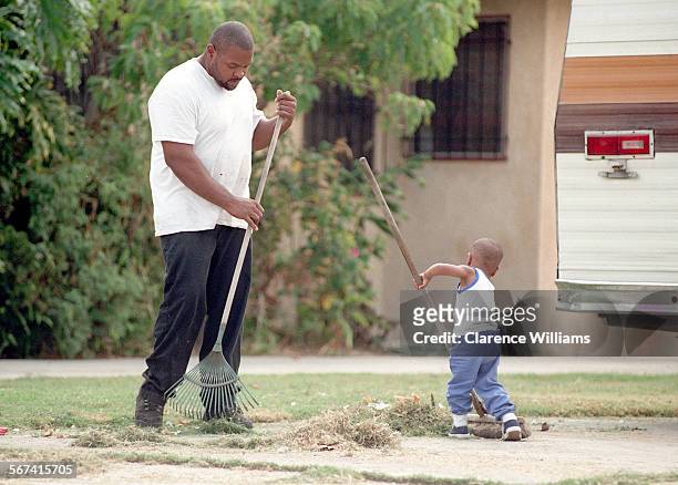 Wild art.0914.CW Leroy Barnes and his son Lamar Barnes tend to yard work in front of their home on 107th Street in Watts. Shot on 9/14/96.