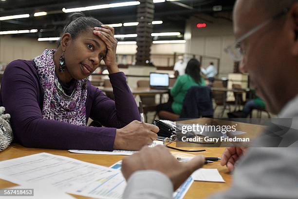 Denise Paul signs up for heath insurance with Glenn Taylor , an enrollment counselor, at an Obamacare enrollment event at Faithful Central Bible...