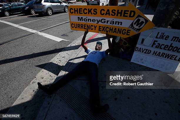 Sign spinner David Harwell grabs attention by dancing and holding an arrow shaped cardboard sign advertising a cash checking establishment at the...