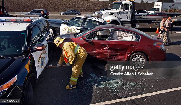 Los Angeles County firefighter/paramedic cleans up the scene as California Highway Patrol officers investigate the scene where two California Highway...
