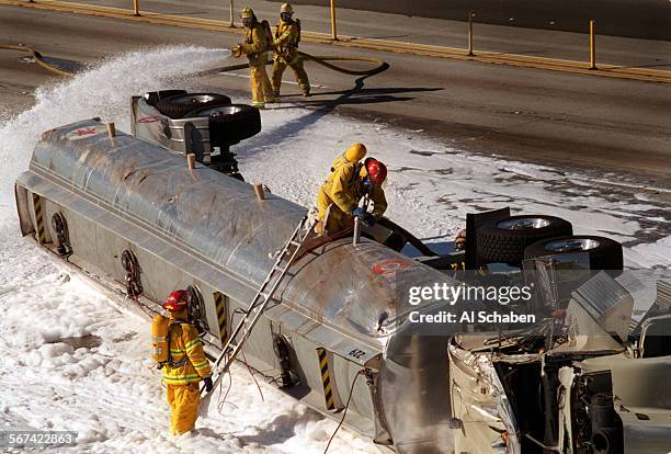 91bigrigcrash.2.1220.ASANAHEIMAn Anaheim fire captain drains gasoline from a tractor trailer that overturned early Saturday morning on the...