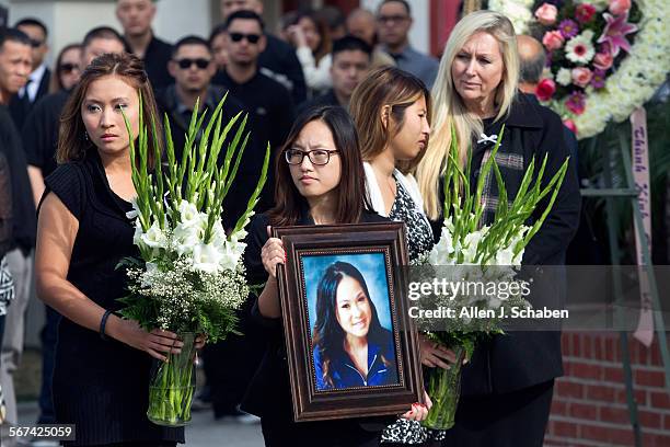 Mourners hold flowers and a portrait of Annie Hung ``Kim'' Pham as they watch pallbearers carry the casket of Pham out of a memorial mass at Blessed...